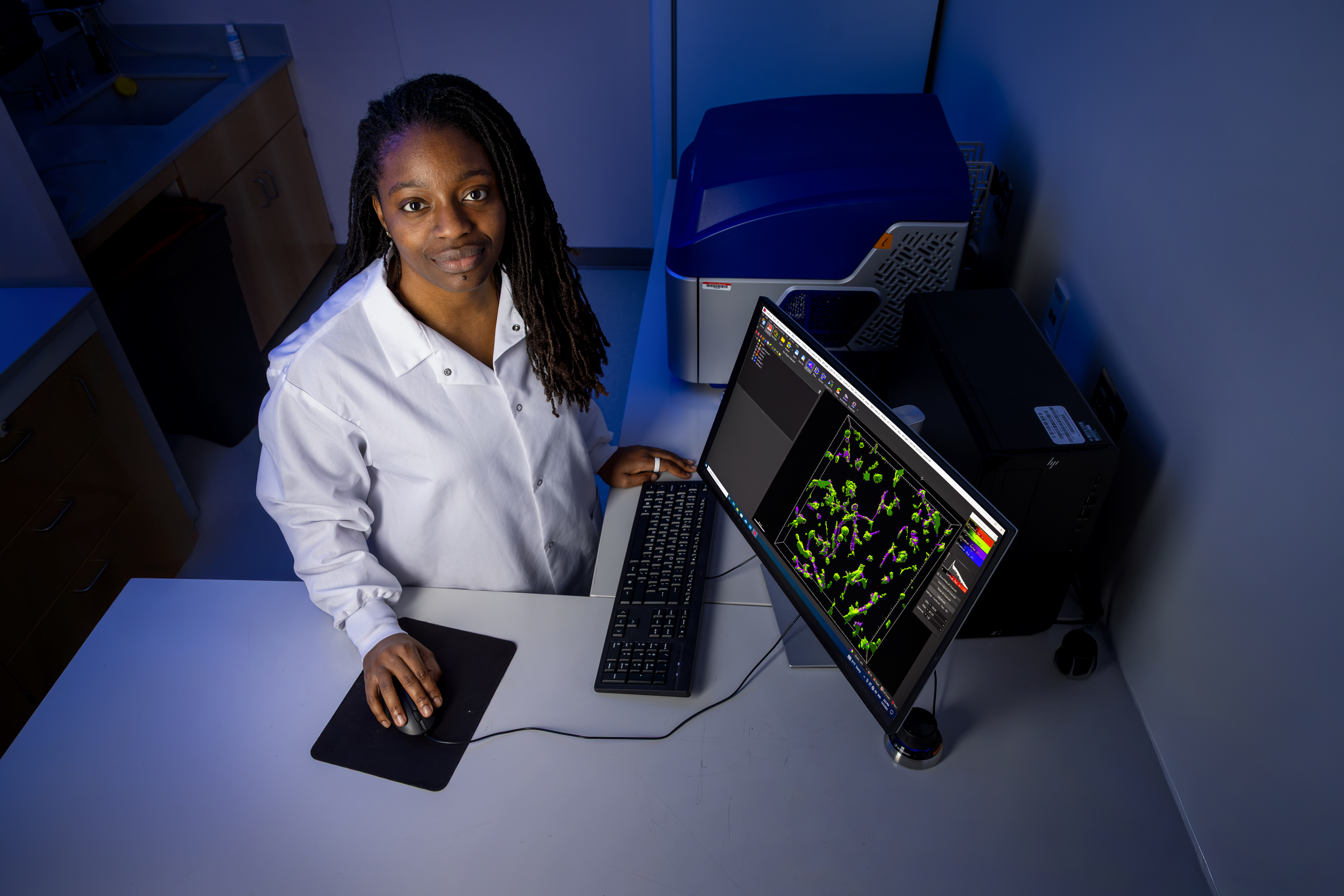 Bioengineering Assistant Professor Erika Moore in her lab with a computer showcasing 3D fibroid models from living cells, with preliminary success blocking its growth with a chemical inhibitor.